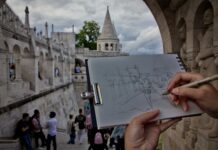 Osoba szkicuje Basztę Rybacką w Budapeszcie, w tle przechodnie