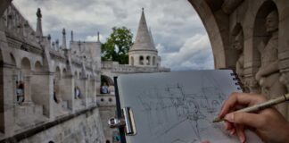 Osoba szkicuje Basztę Rybacką w Budapeszcie, w tle przechodnie