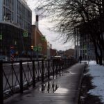 Zimowa ulica w centrum miasta ze śniegiem i odbiciami na mokrym chodniku