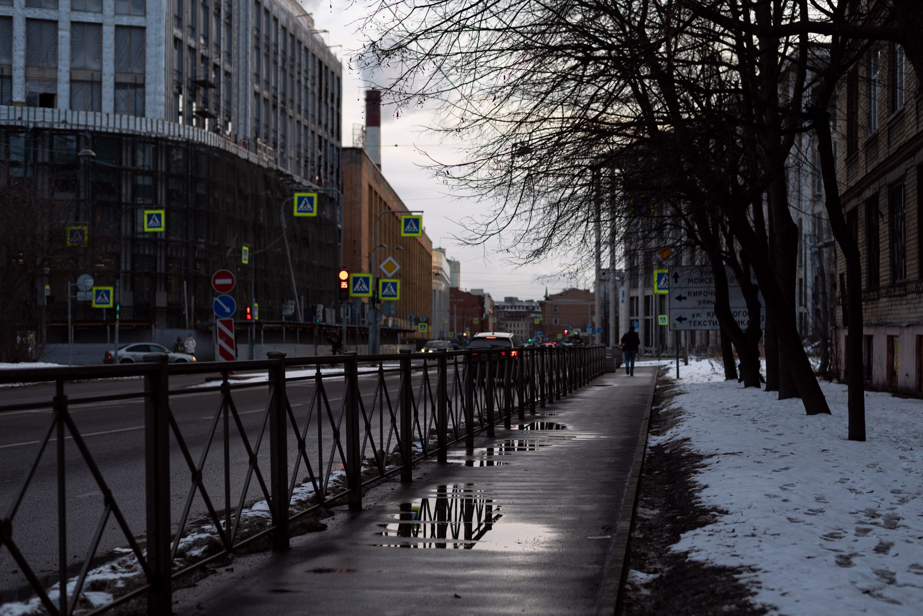 Zimowa ulica w centrum miasta ze śniegiem i odbiciami na mokrym chodniku